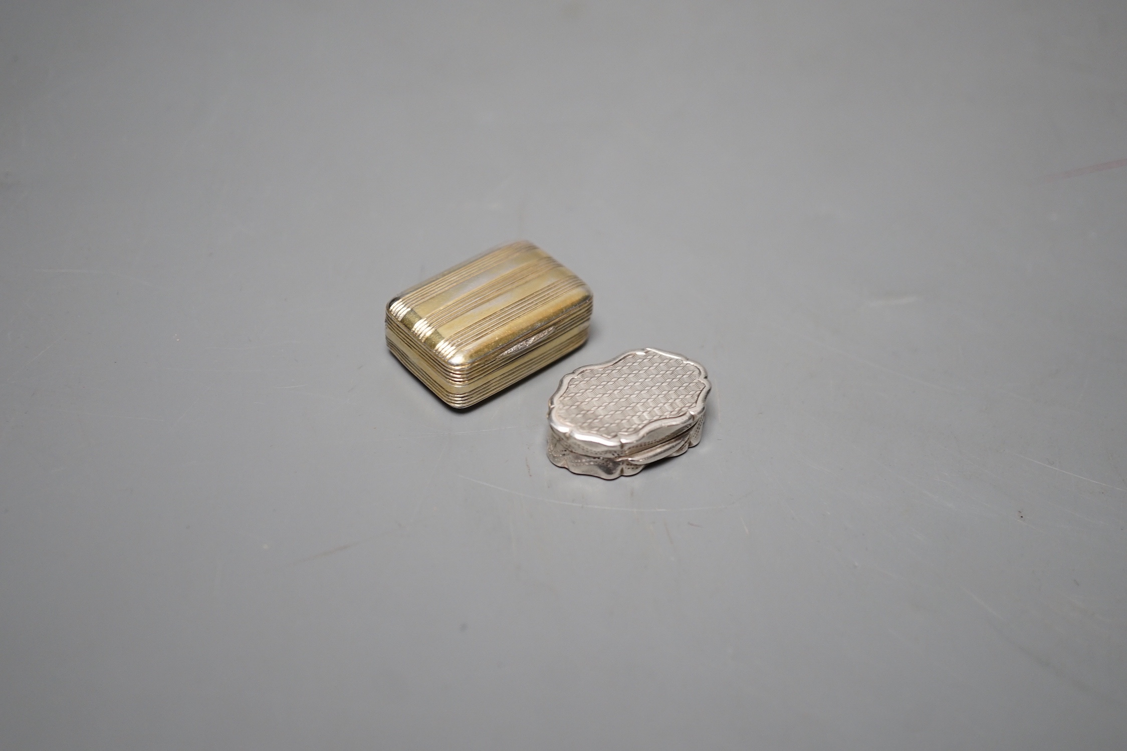 A George III silver gilt vinaigrette, TB, London, 1801, 30mm and a late shaped oval silver vinaigrette by George Unite, 27mm.